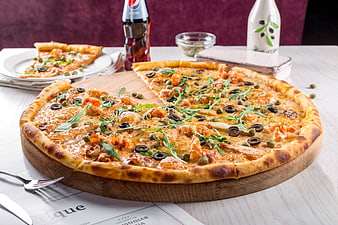 Delicious pizza with olives and arugula on wooden board
