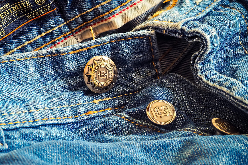 Close-up of vintage denim jeans with brass buttons and stitching