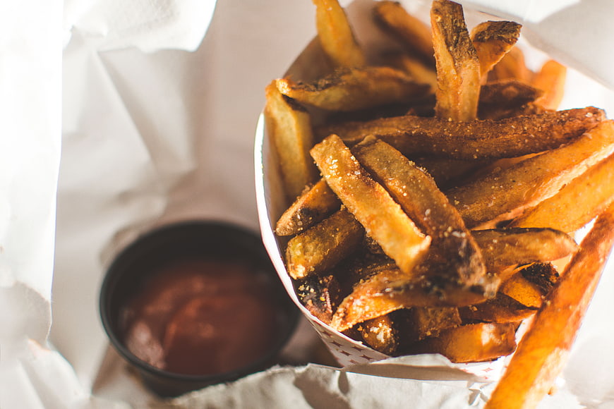 Crispy seasoned french fries with ketchup in paper boat