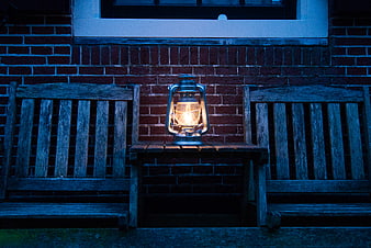 Vintage lantern glowing on wooden bench at night