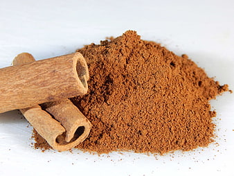 Ground Cinnamon Powder And Sticks On White Surface