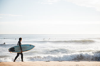 Surfer Walking on Beach with Blue Surfboard