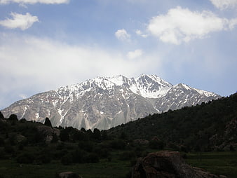 Snow-capped mountain peak with green valley and blue sky