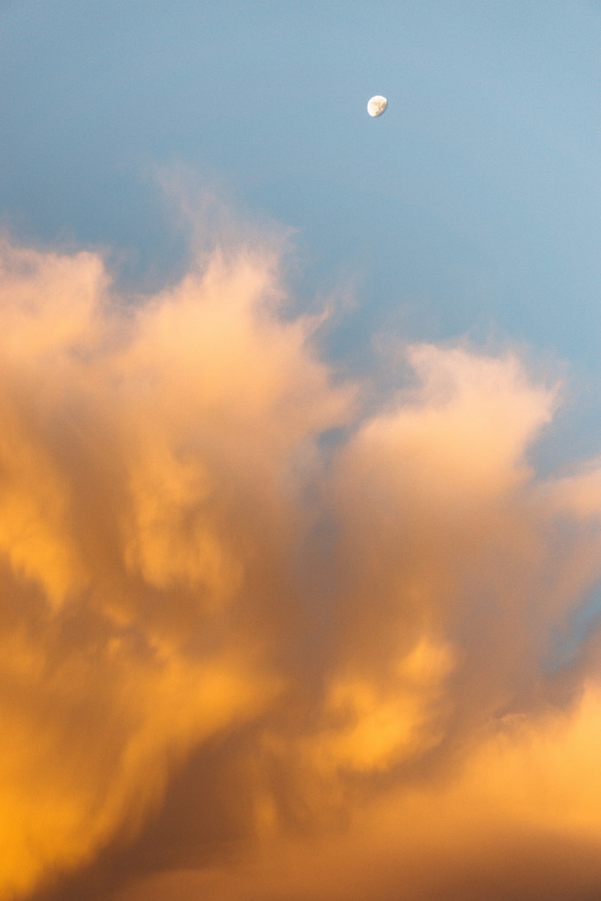 Golden sunset clouds with moon in blue sky