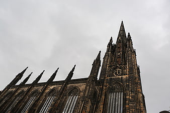 Gothic church spire and clock tower against cloudy sky