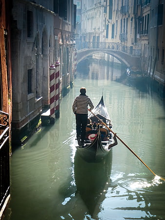 Gondolier rowing through a misty Venice canal