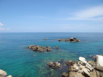 Tropical turquoise sea with rocky outcrops and clear blue sky