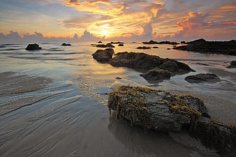 Dramatic Sunset Over Rocky Beach with Long Exposure Water