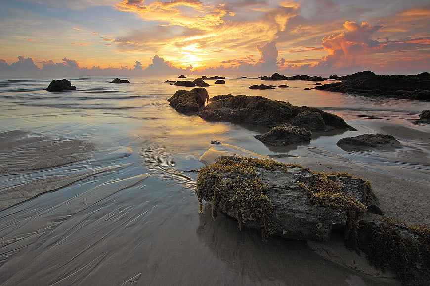 Dramatic Sunset Over Rocky Beach with Long Exposure Water