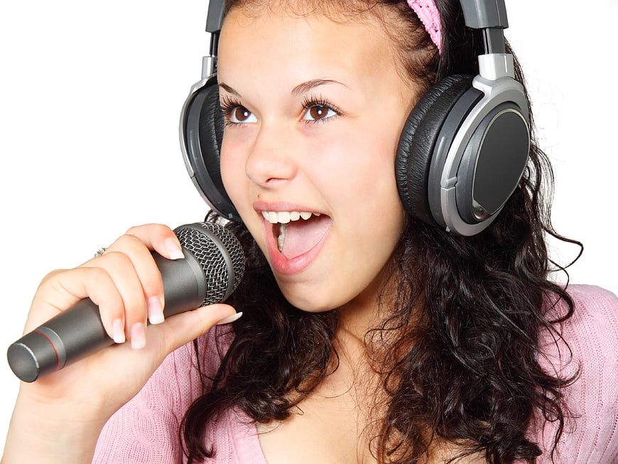 Teenage girl singing into microphone with headphones