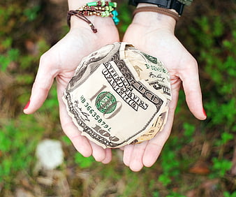Hands holding crumpled hundred dollar bill outdoors