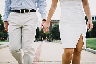 Couple holding hands walking outdoors in white and light blue attire