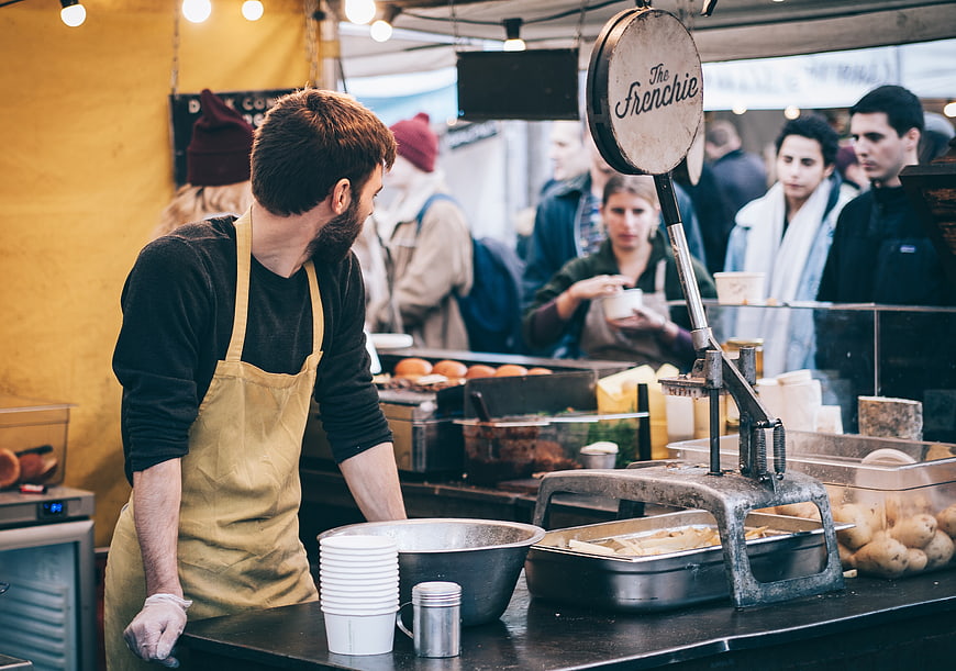 Chef preparing food at a busy outdoor food market stall