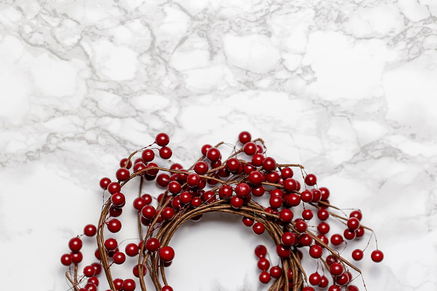 Red berry wreath on white marble background
