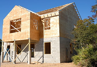 Two-story house under construction with wooden frame and concrete foundation