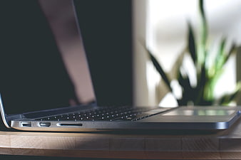 Side View of Closed Laptop on Wooden Desk