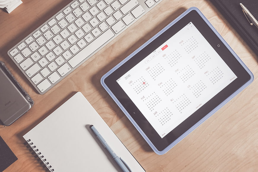 Flat lay of tablet with calendar on wooden desk