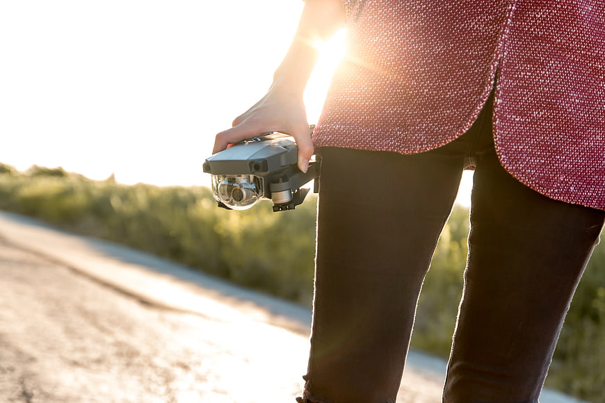 Woman holding drone controller on sunny road