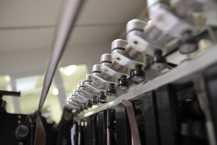 Close-up of industrial printing press grippers and mechanical components