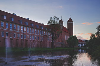 Historic Brick Castle with Towers and Fountains at Sunset