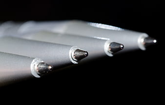 Macro close-up of four ballpoint pen tips on black background