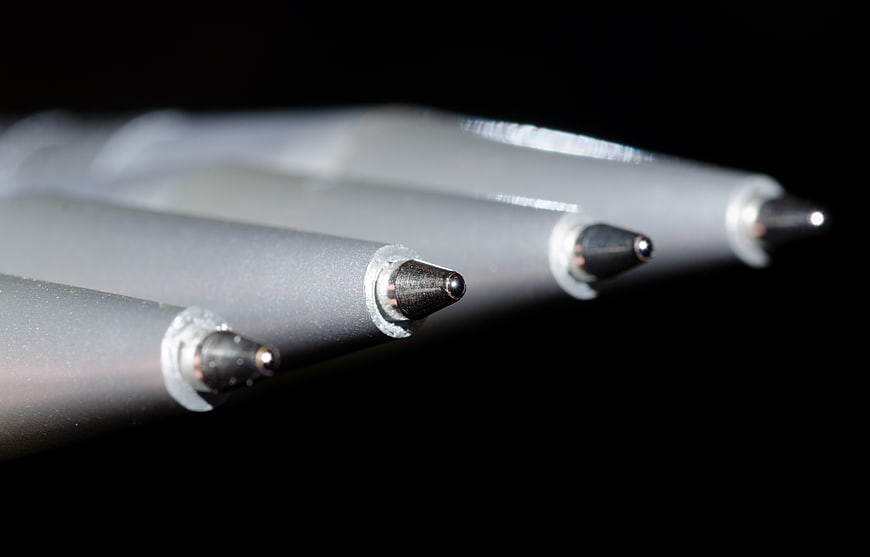 Macro close-up of four ballpoint pen tips on black background