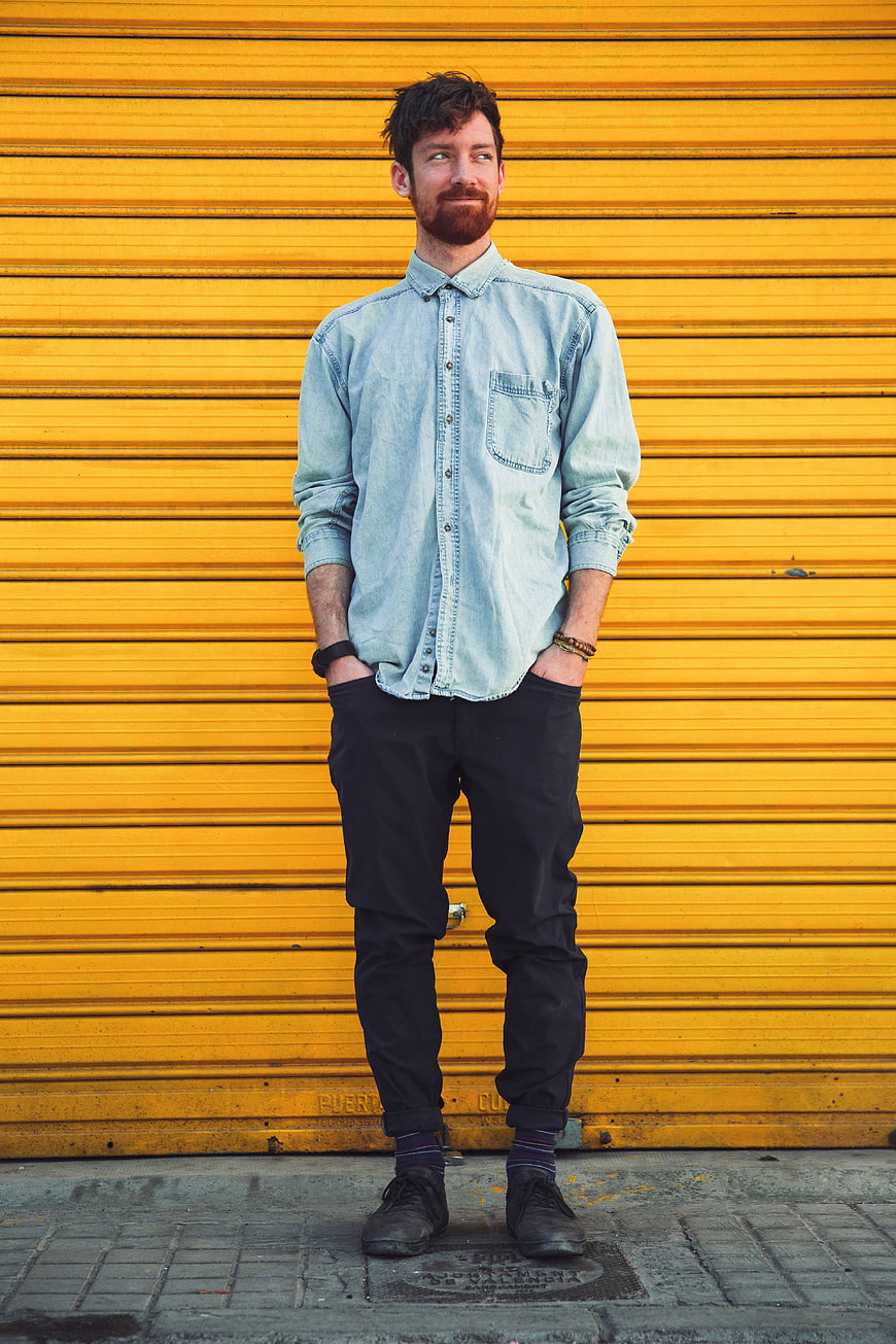 Man in Denim Shirt Standing Against Yellow Wall