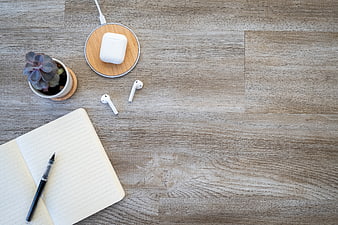 Minimalist workspace flat lay with wireless earbuds and notebook