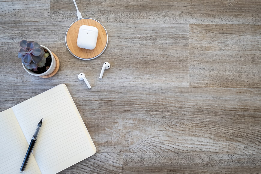 Minimalist workspace flat lay with wireless earbuds and notebook