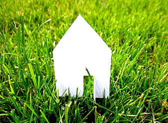 White paper house silhouette standing in green grass