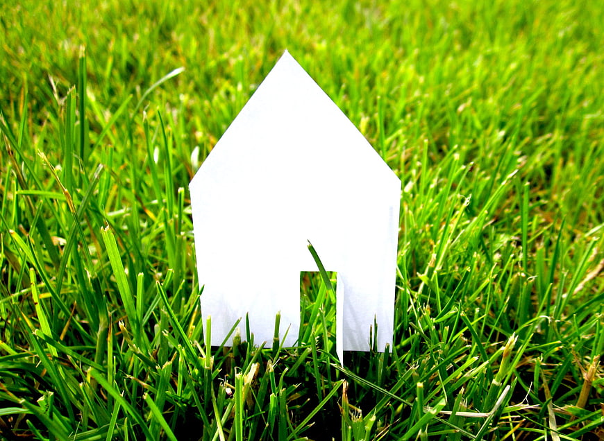 White paper house silhouette standing in green grass