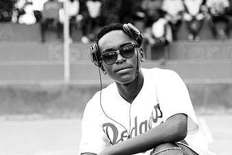 Young Black Man with Headphones and Sunglasses Sitting Outdoors