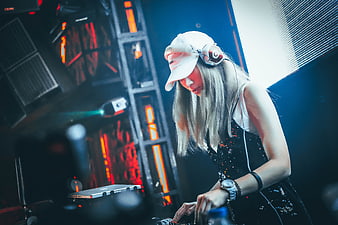 Female DJ mixing music at nightclub with headphones