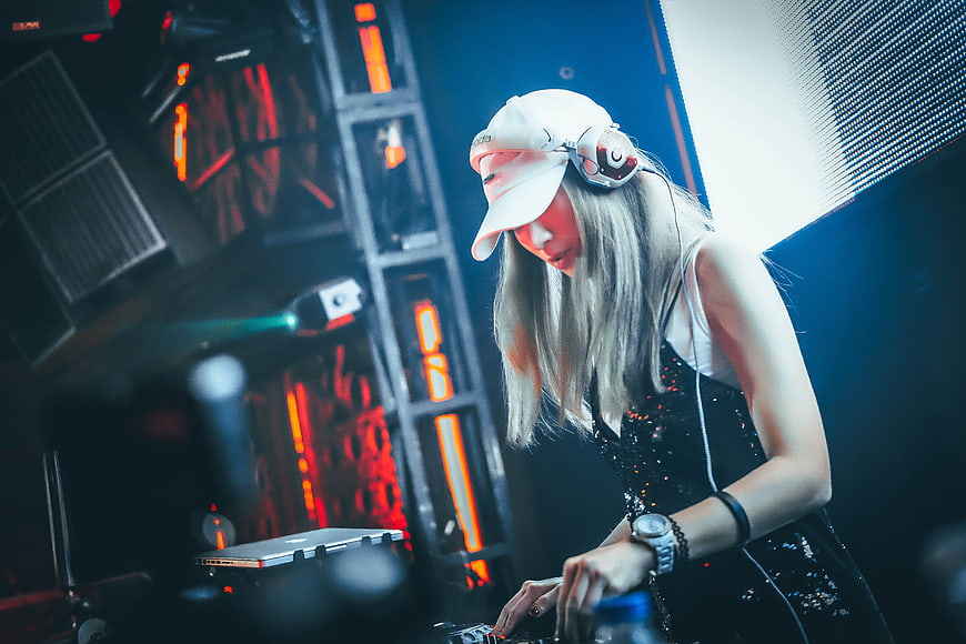 Female DJ mixing music at nightclub with headphones