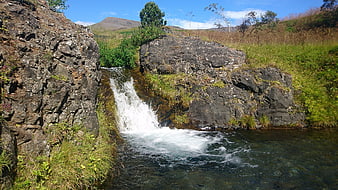 Small waterfall cascading over rocks in a lush green landscape