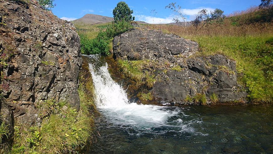 Small waterfall cascading over rocks in a lush green landscape