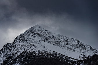 Dramatic Snow-Covered Mountain Peak Under Dark Stormy Clouds