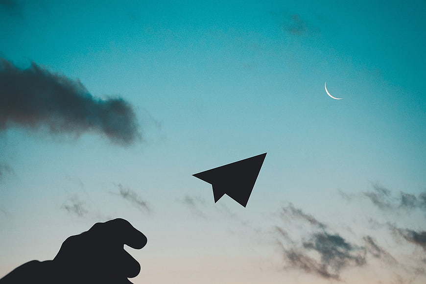 Silhouette of Hand Throwing Paper Plane at Dusk