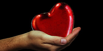 Hand Holding Shiny Red Heart on Black Background