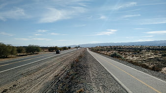 Desert highway with bike path and distant mountains