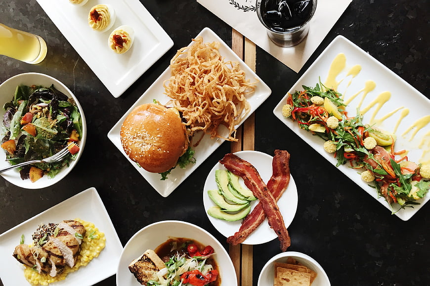 Overhead view of gourmet dinner spread with burger and salads