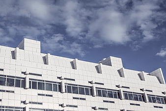 Modern white geometric building facade against blue sky