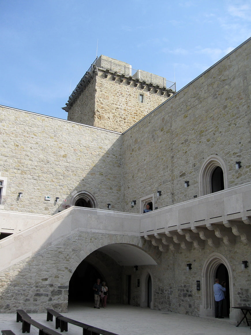 Stone castle courtyard with arches and tower