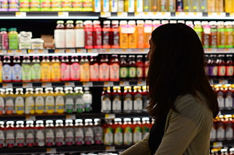 Woman shopping for drinks in grocery store aisle
