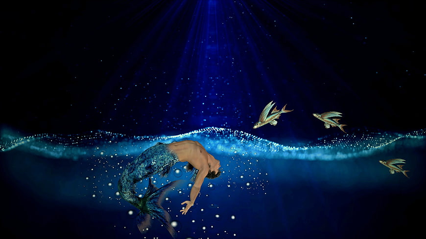 Mystical male merman swimming underwater with flying fish and light rays