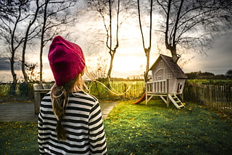 Girl in Pink Beanie Looking at Playhouse in Garden