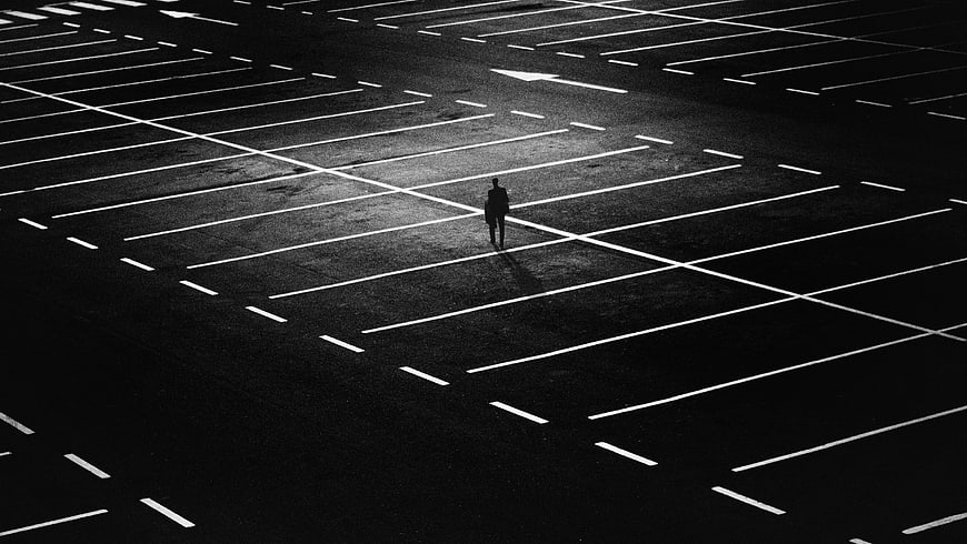 Silhouette of man standing in empty parking lot at night