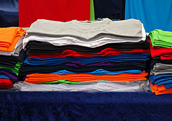 Colorful stacks of folded t-shirts at a market stall
