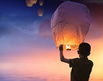 Boy Releasing Glowing Sky Lantern at Sunset