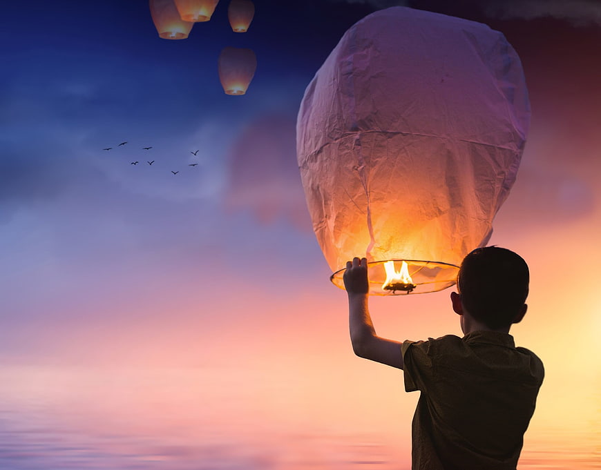Boy Releasing Glowing Sky Lantern at Sunset